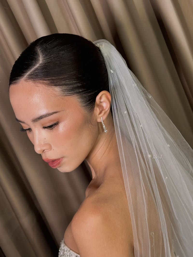 Bride with a sleek low bun and a long veil, looking down