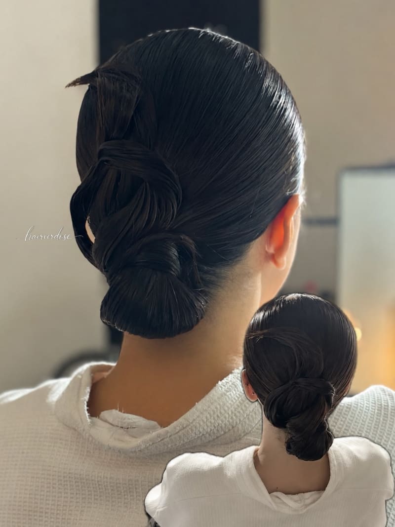Two sleek knotted low buns seen from behind