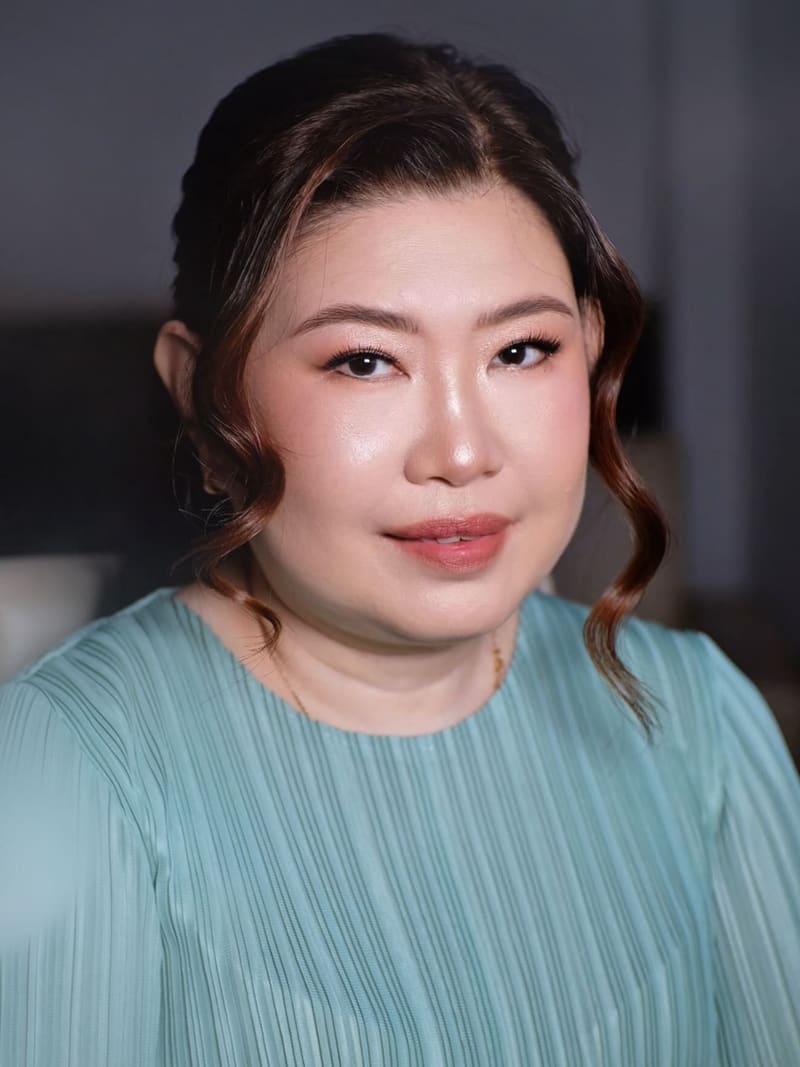 Woman in a teal dress with soft curls framing her face