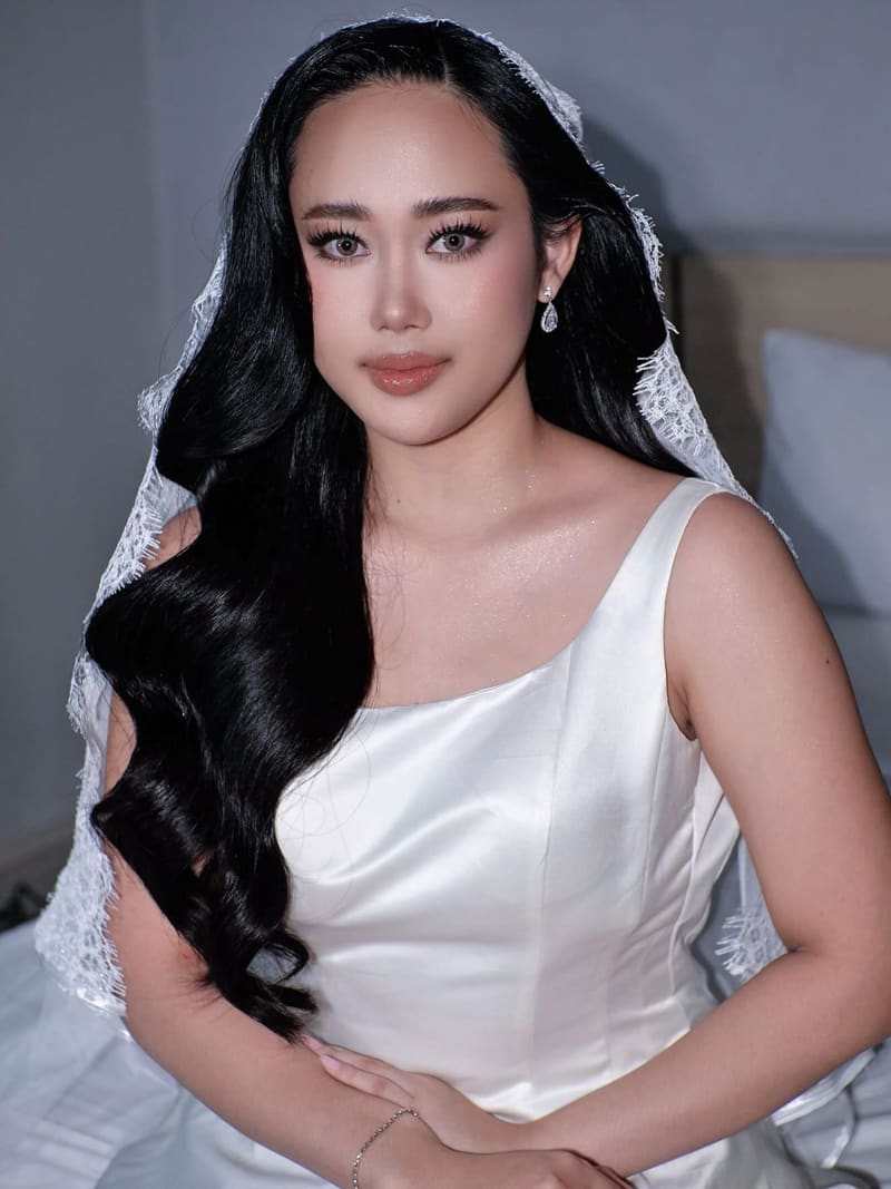 Bride with long glossy waves over one shoulder under a lace veil