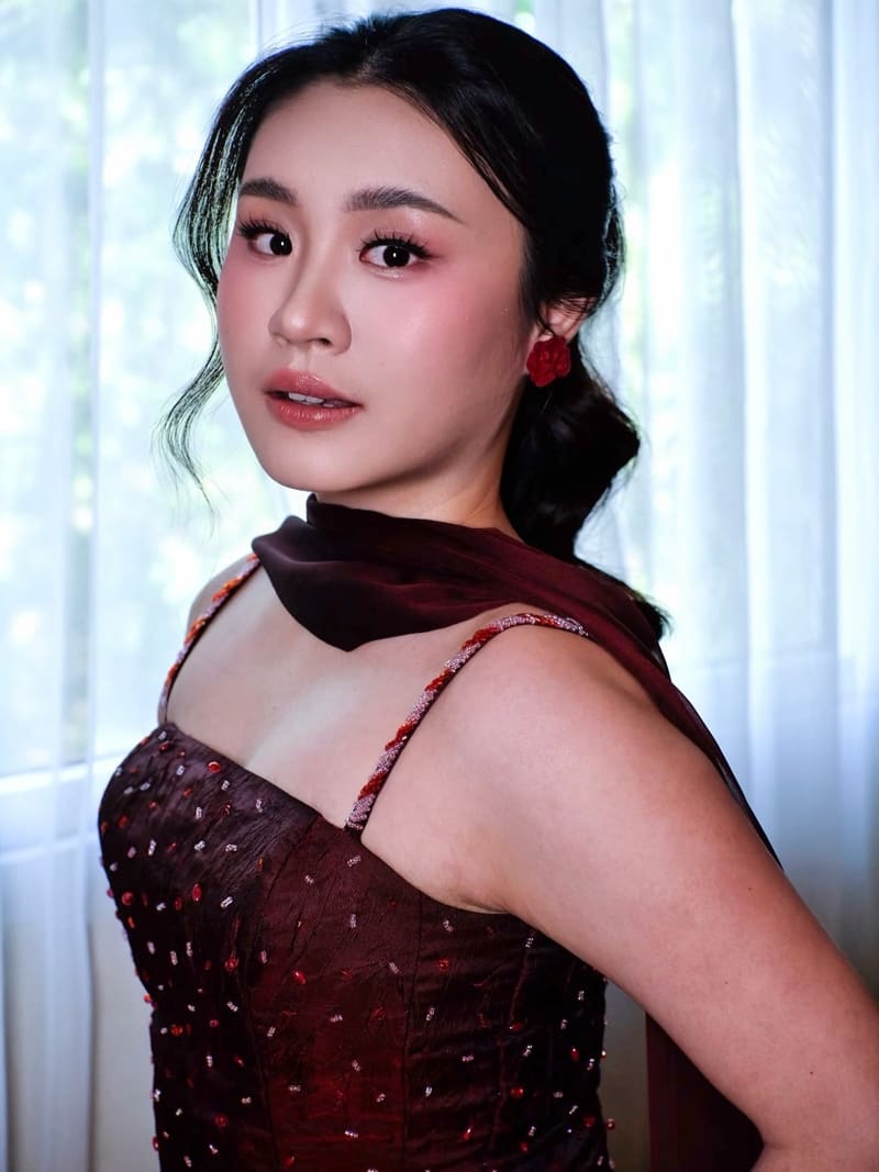 Woman in a deep red dress with a low twisted bun and loose strands